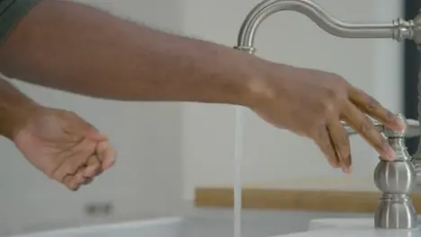 Man Cleaning His Hands with Soapy Water Under Running Tap 