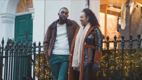 Couple Outside Clothes Store Decorated For Christmas On Shopping Trip To London 