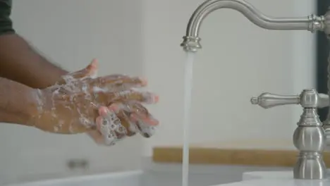 Man Cleaning His Hands with Soap Under Running Tap Water