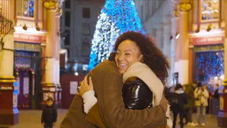 Couple Hugging As They Meet In Front Of Christmas Tree In Leadenhall Market London UK