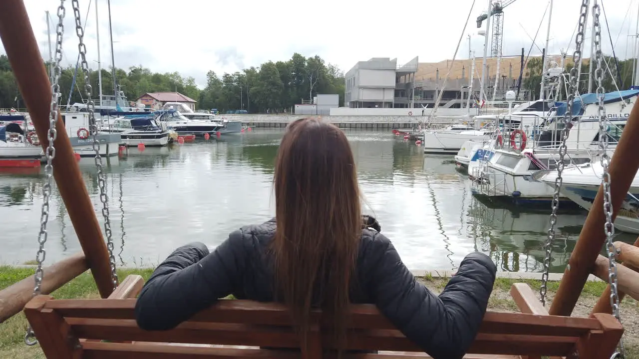 Cinematic shot of a woman swinging and in the background you can see a sports dock