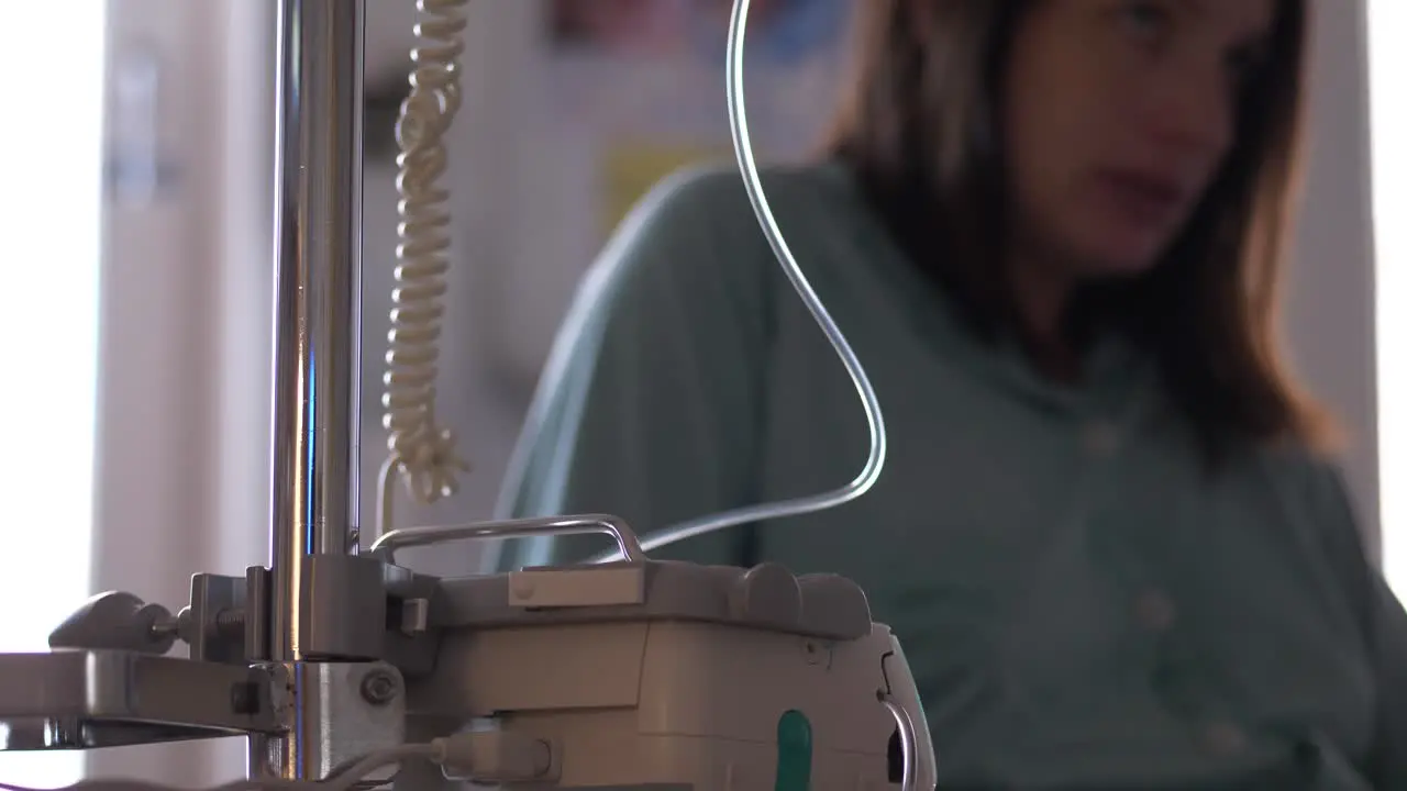 Sick woman looks apprehensive while connected to IV intravenous drip