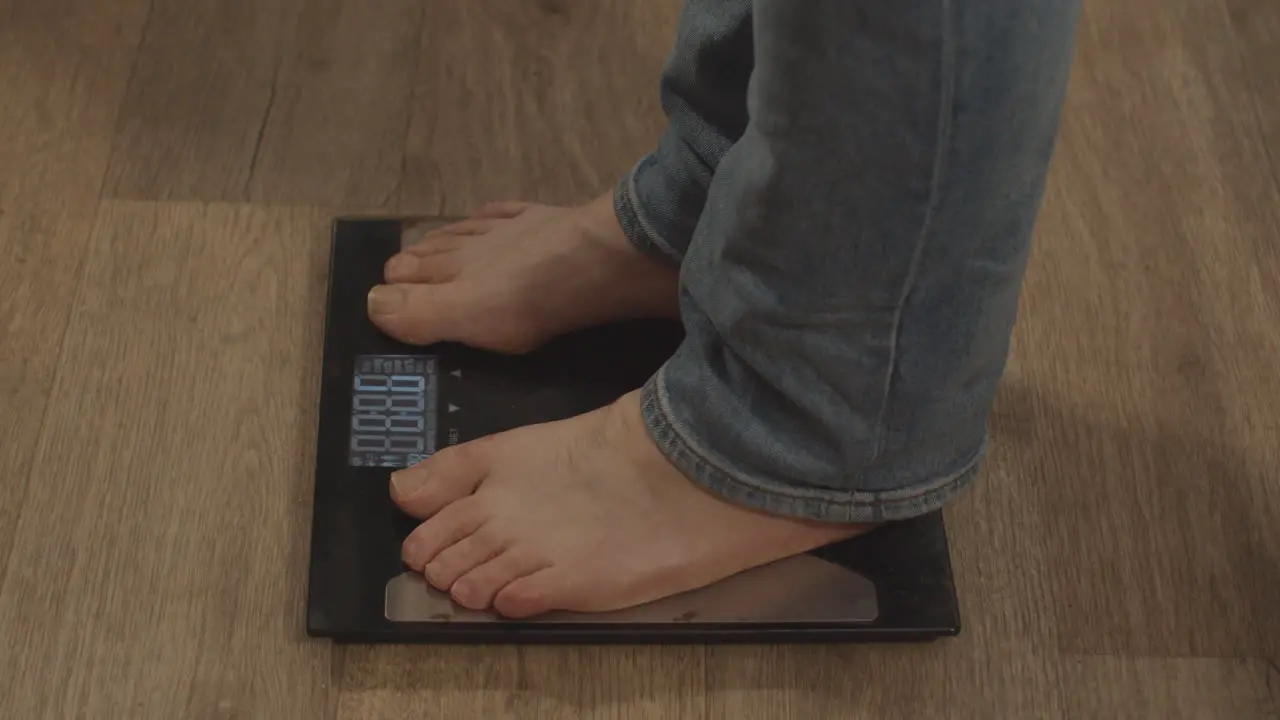 High angle view of bare feet stepping onto weight scale