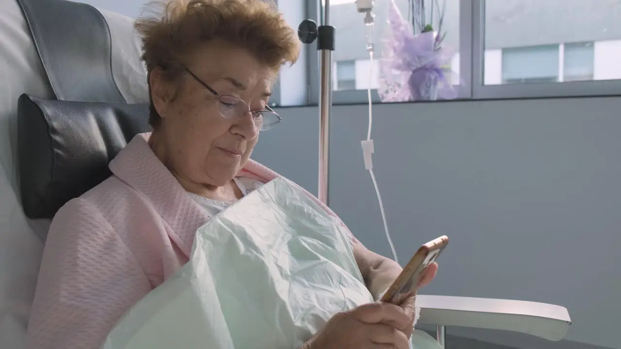 Hospital room Close up Elderly woman holding mobile phone intravenous drip Medication