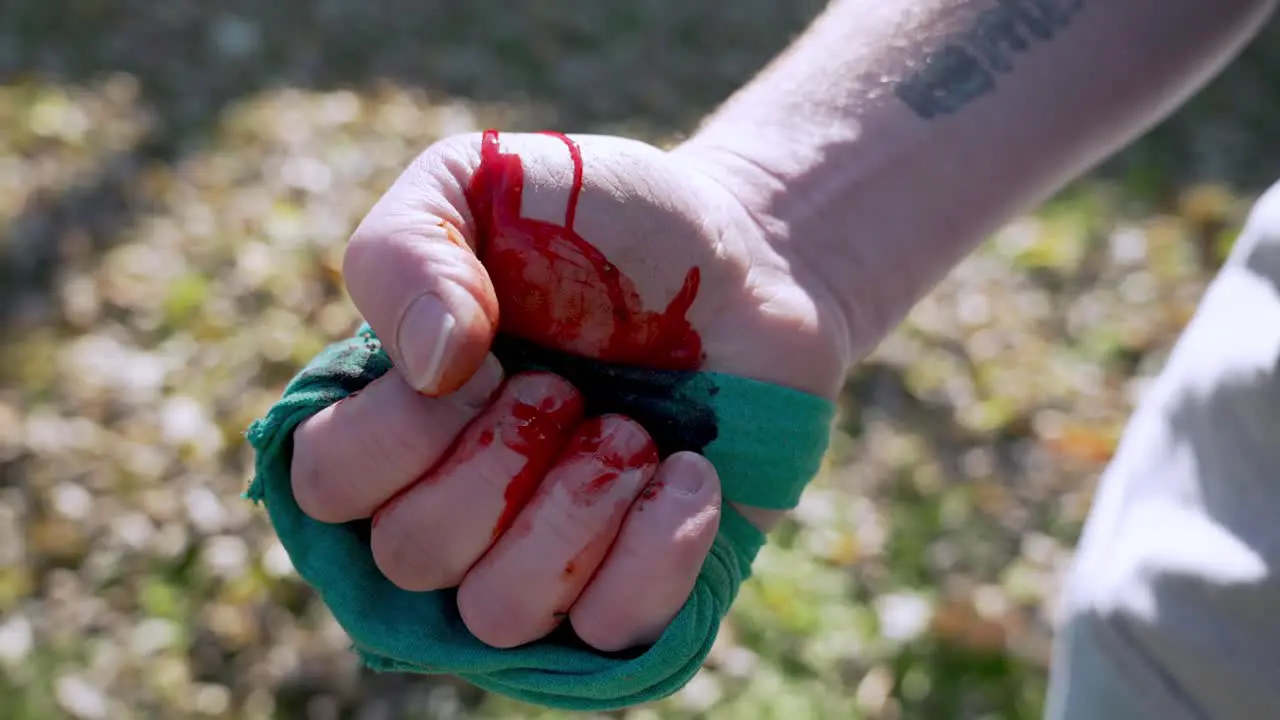 Man closes hand with tightened textile to stop the bleed Blurred grass background