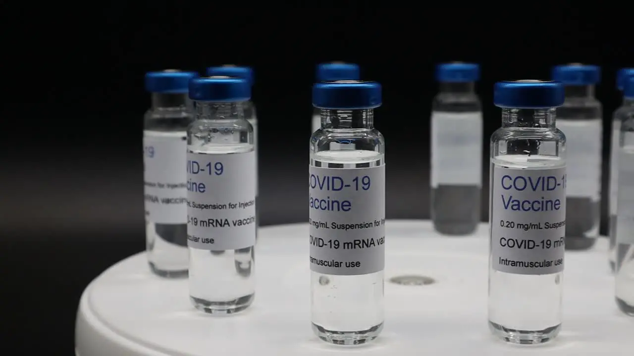 Glass vials with Covid-19 Vaccine on rotating display isolated on black background