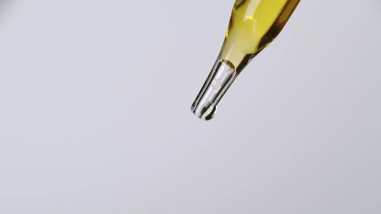 A simple pipette dropper with yellow liquid and a bright white background