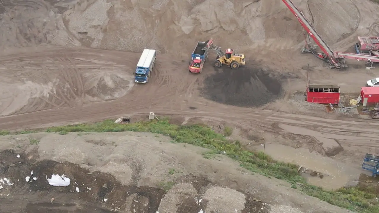 Aerial of excavator dumping sand in truck close