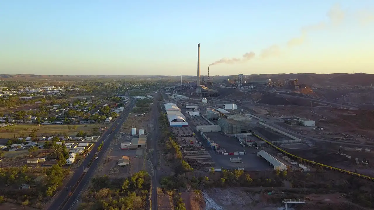 Vertically rising drone footage of large mining complex with two large smoke stacks one of which has smoke coming out