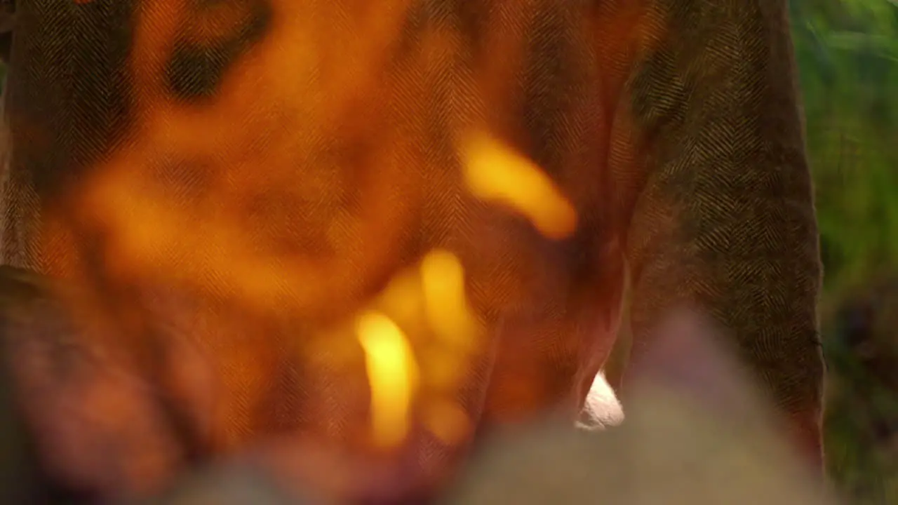 Handheld slow motion shot of a man fanning a forge with and ancient bellow