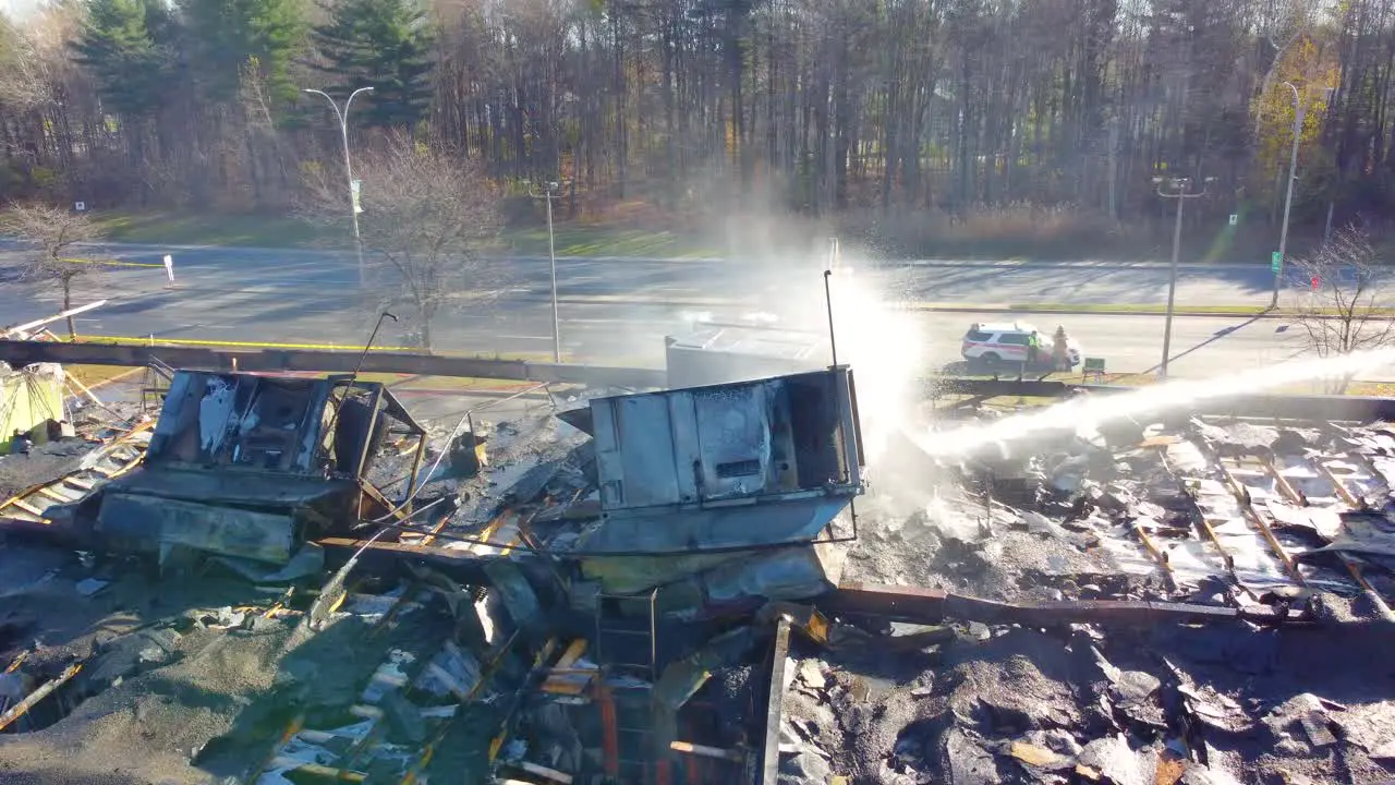 Aerial View Of Roof Fire Collapse Of Warehouse With Fire Department Using Ladder To Extinguish Flames