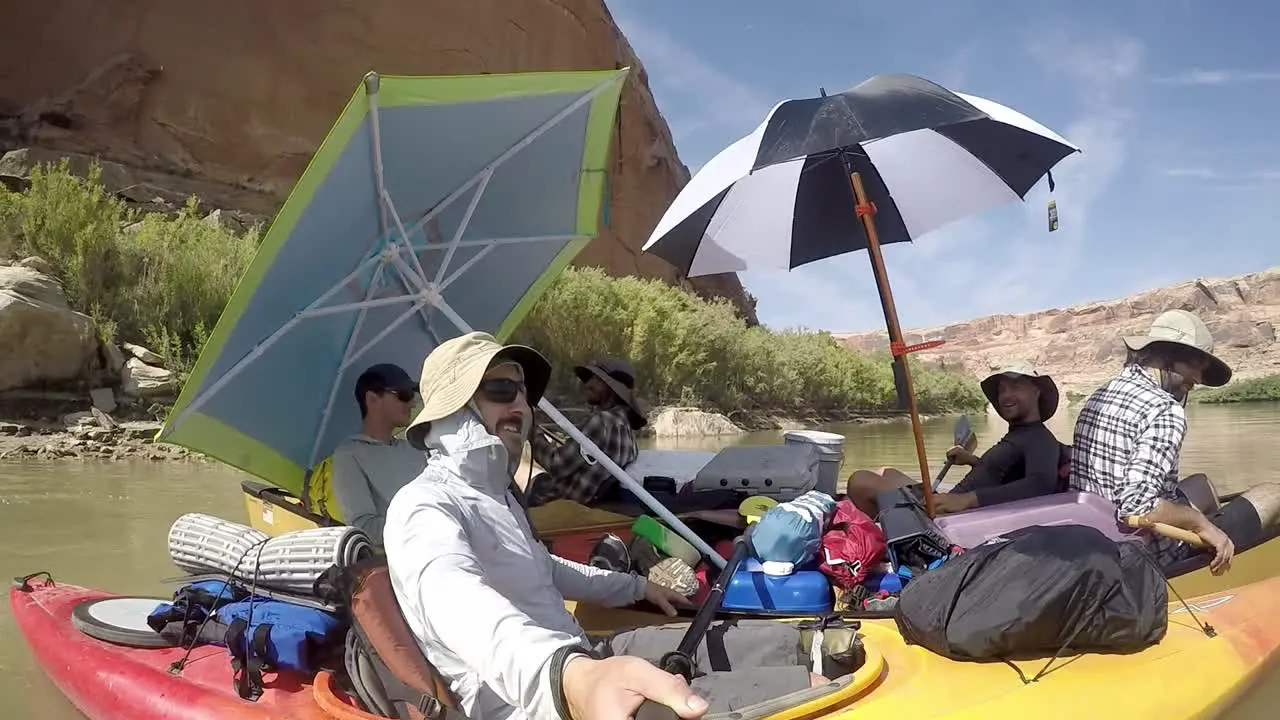 Guys floating together in canoes on river in Utah