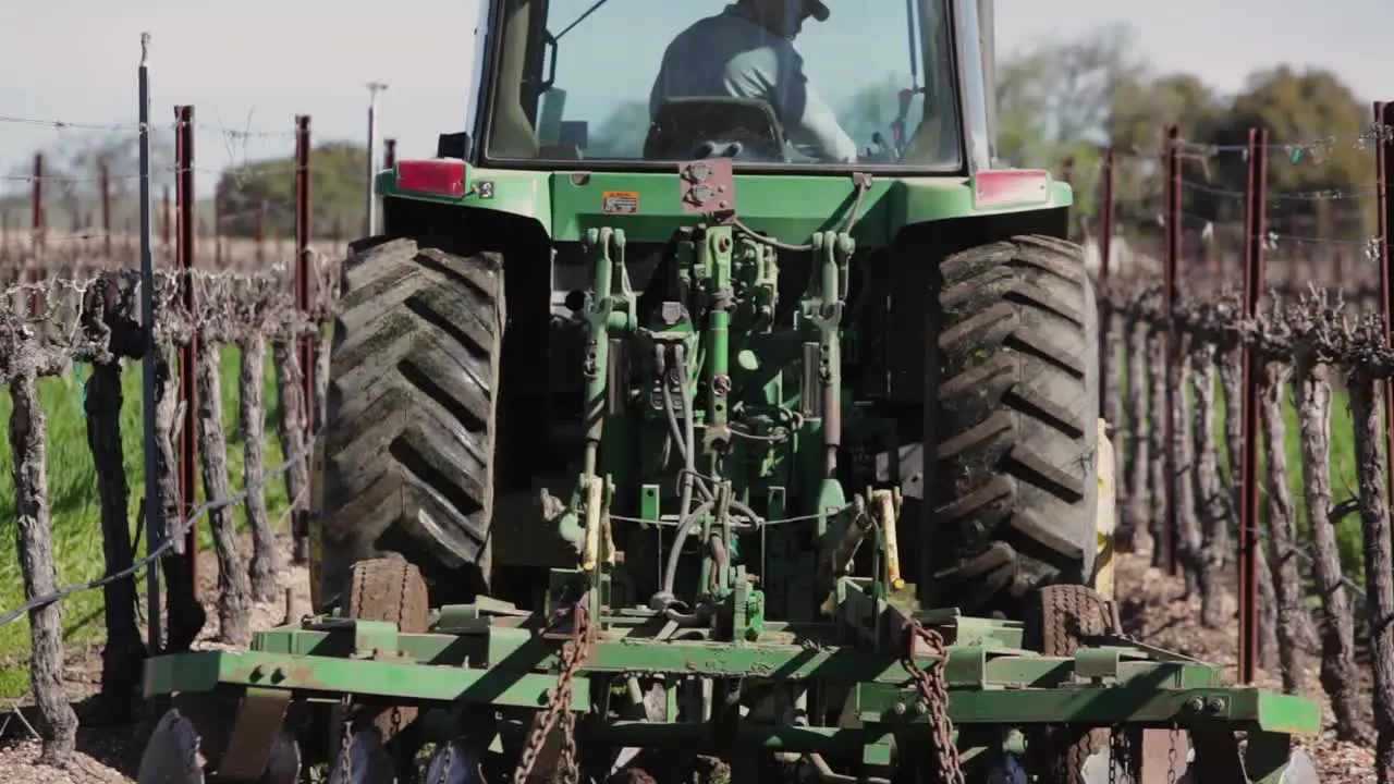 A tractor mows a cover crop between rows of grapes on a California vineyard 1