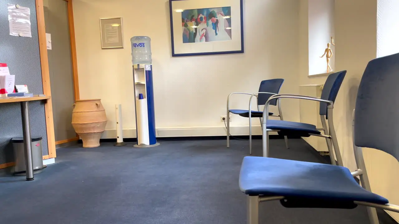 Empty waiting room at doctor office with chairs soda fountain and sunlight