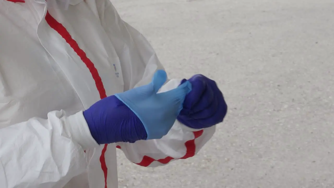 A medical worker in full PPE puts on a double layer of gloves at a coronavirus testing center during the COVID-19 pandemic