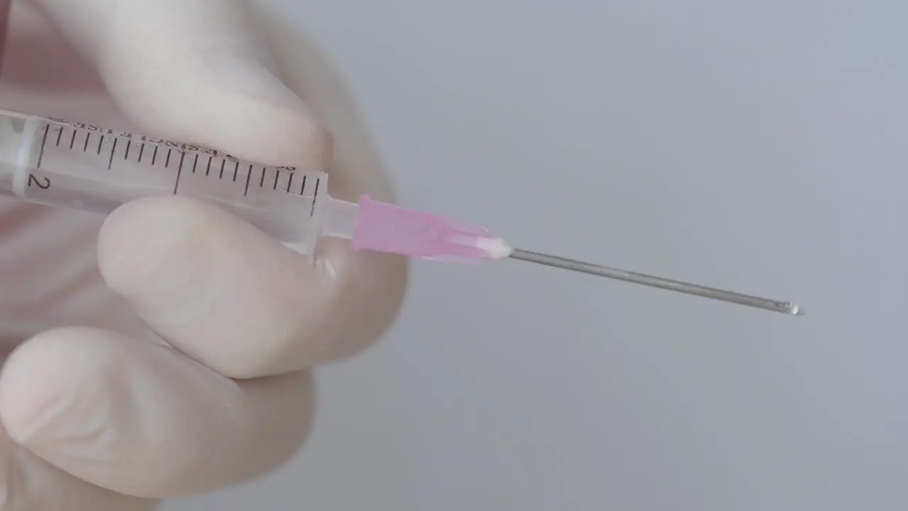 Droplets On Hypodermic Syringe While Pressing With Hand In Surgical Glove Close Up Shot