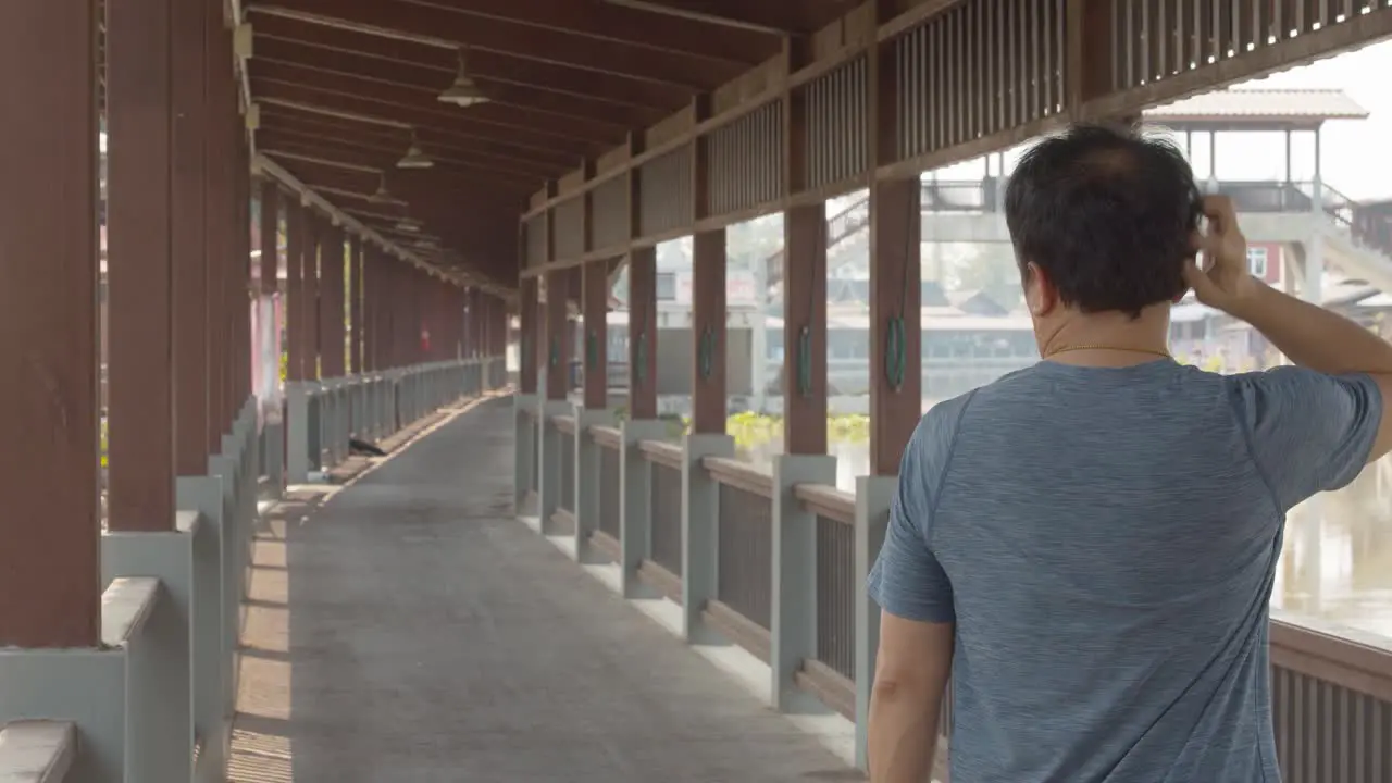 Balding man on a boardwalk or dock can't stop scratching his itchy scalp brushes the dandruff off his shirt