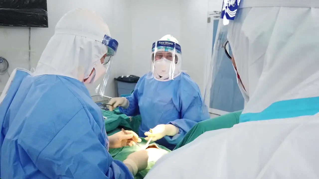 Asian Surgeon Wear PPE Perform Upper Body Surgery For Contagious Patient In Operating Room