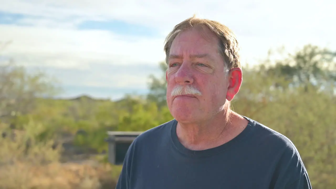 Portrait of Caucasian senior man outdoors taking off protective face mask breathing deeply fresh air