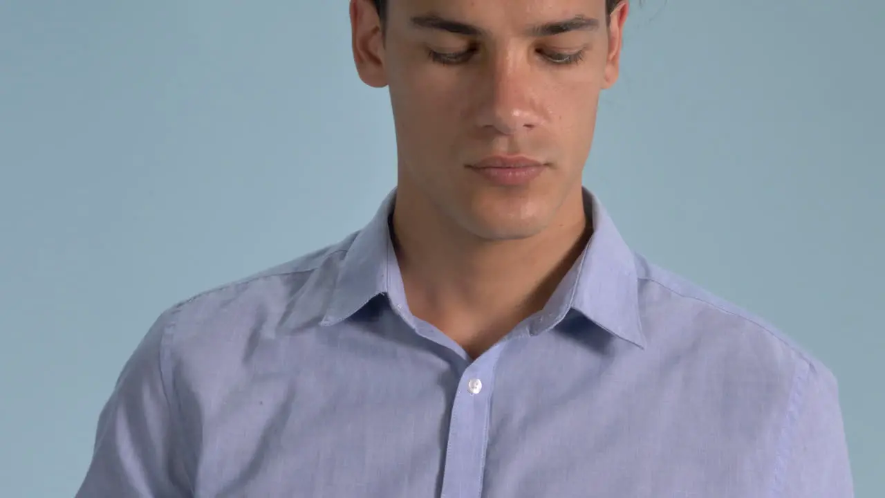 A Handsome Man Demonstrating The Proper Wearing Of Surgical Face Mask Standing Against Light Blue Background Coronavirus Pandemic Closeup Shot