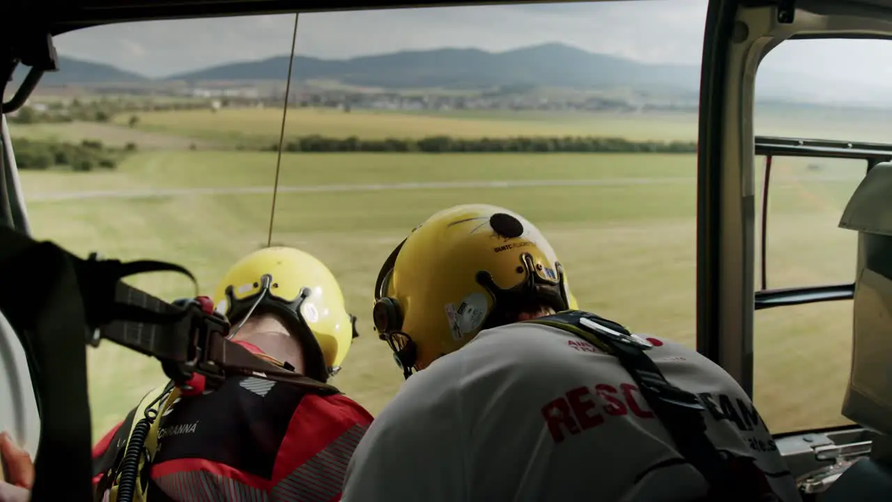 Two rescuers with yellow helmet hovering in rescue helicopter with open door