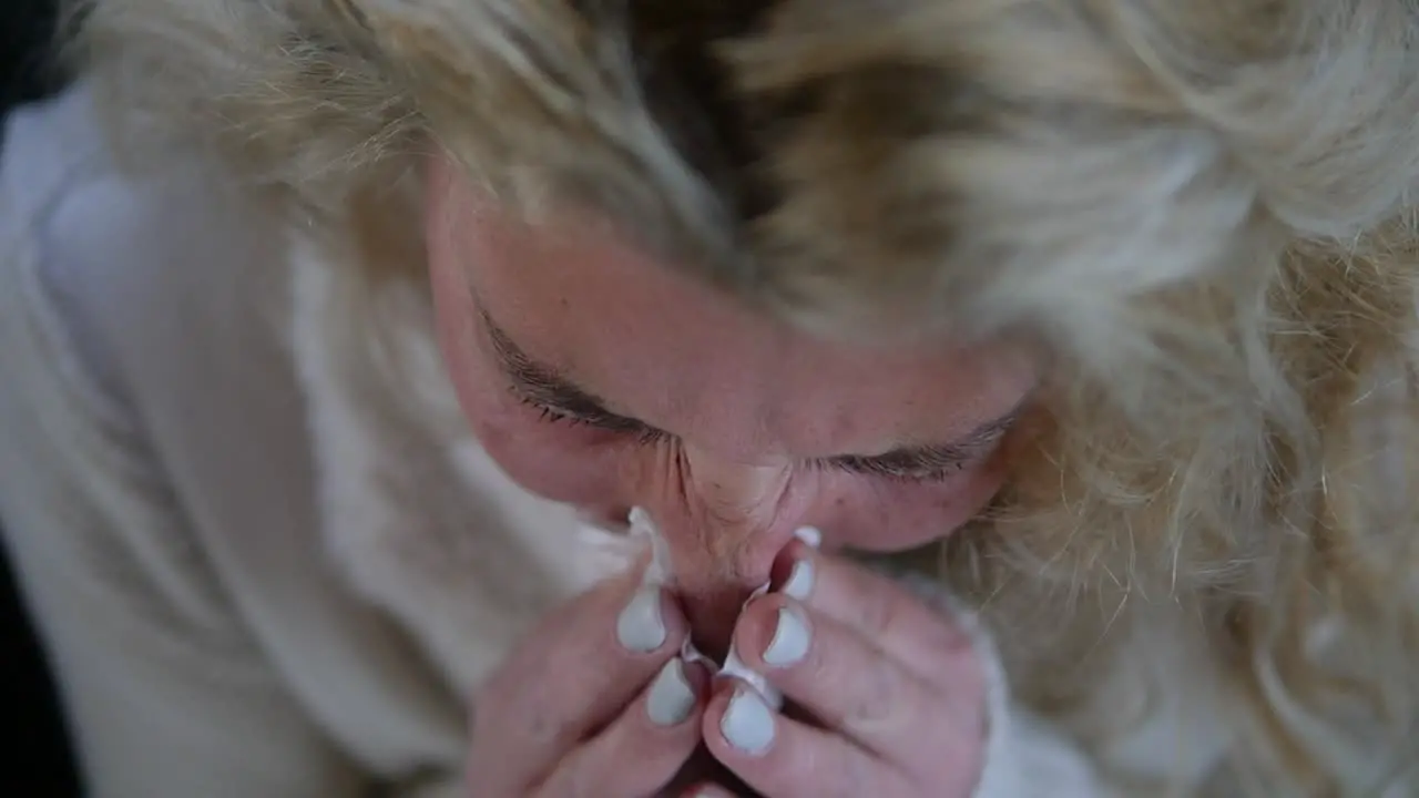 Extreme close-up of a sick woman sneezing into a tissue