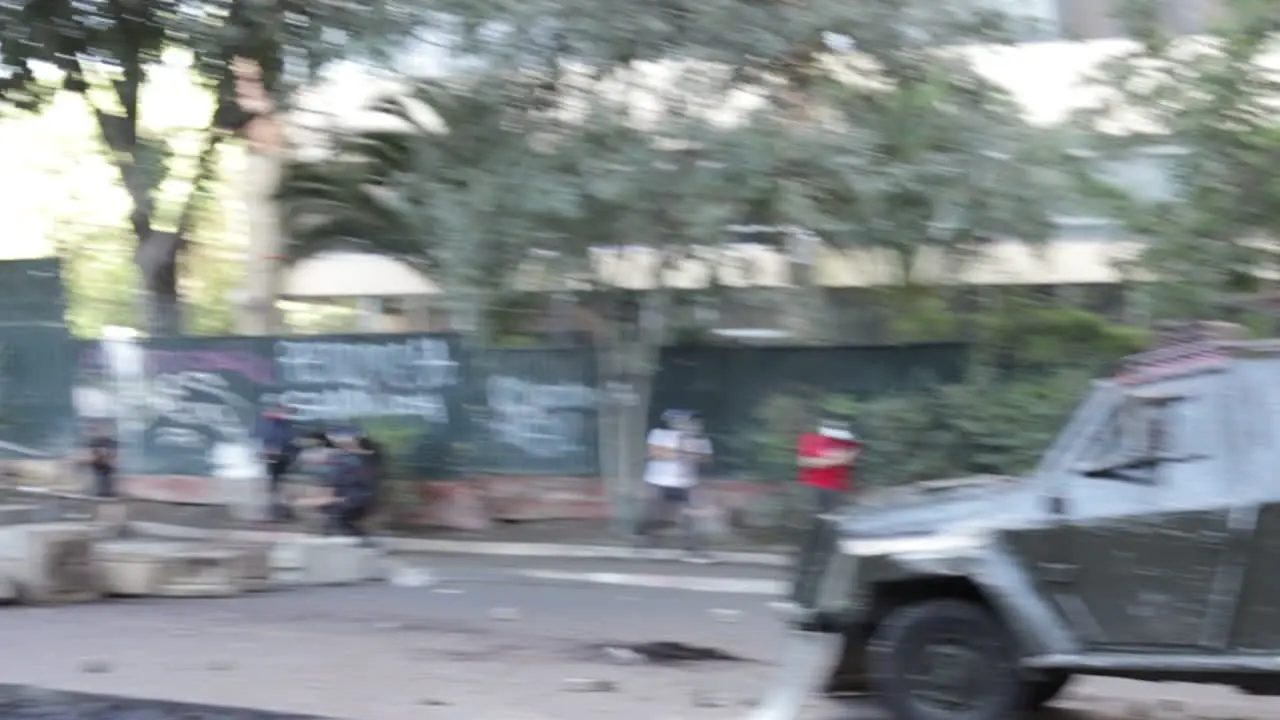 Rioter throws molotov cocktail at riot police hiding behind an armored vehicle