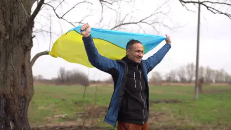 Ukrainian man Young smiling man holding ukrainian flag No war Support for Ukraine Patriotic Spirit rising hand of Ukraine flag freedom ukraine Nature background