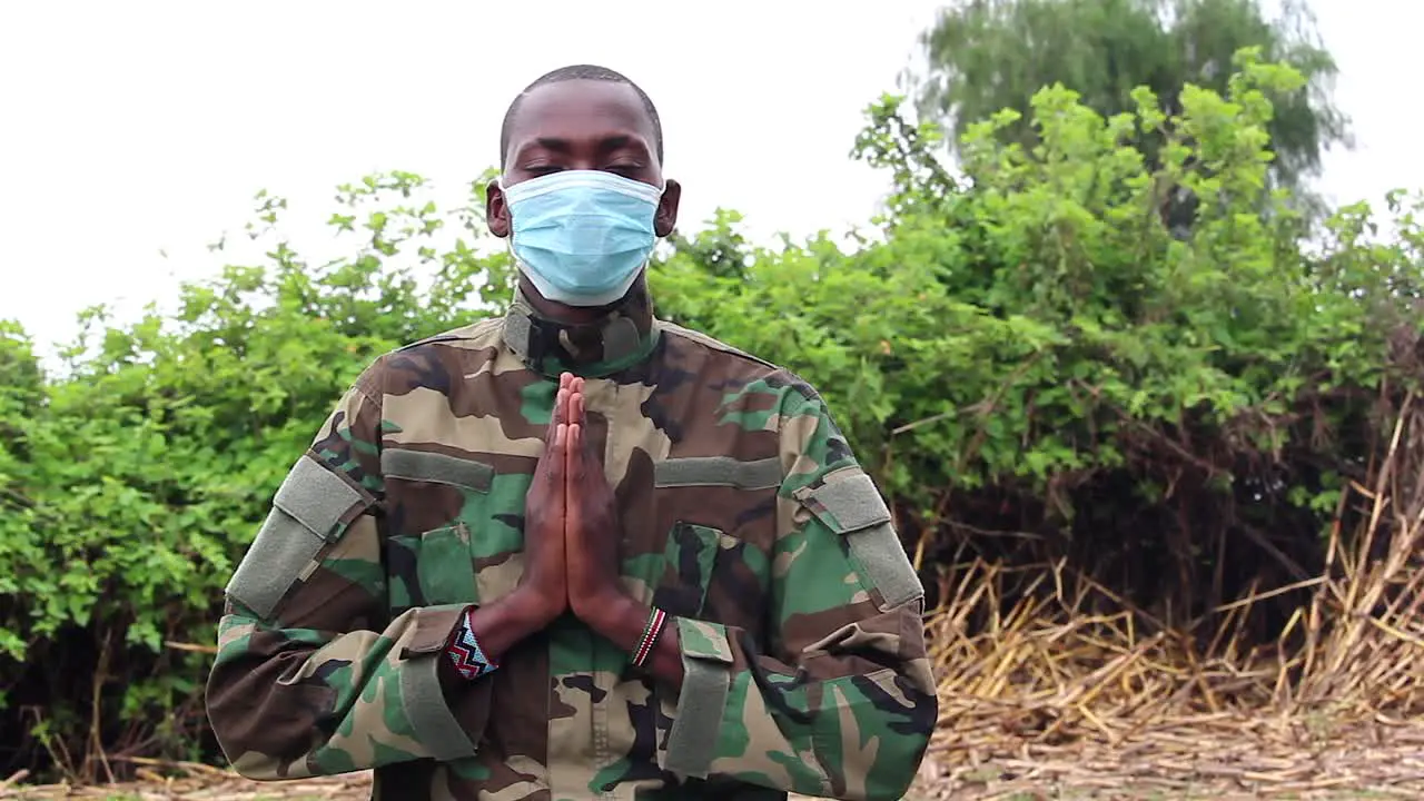 African soldier praying with covid mask on