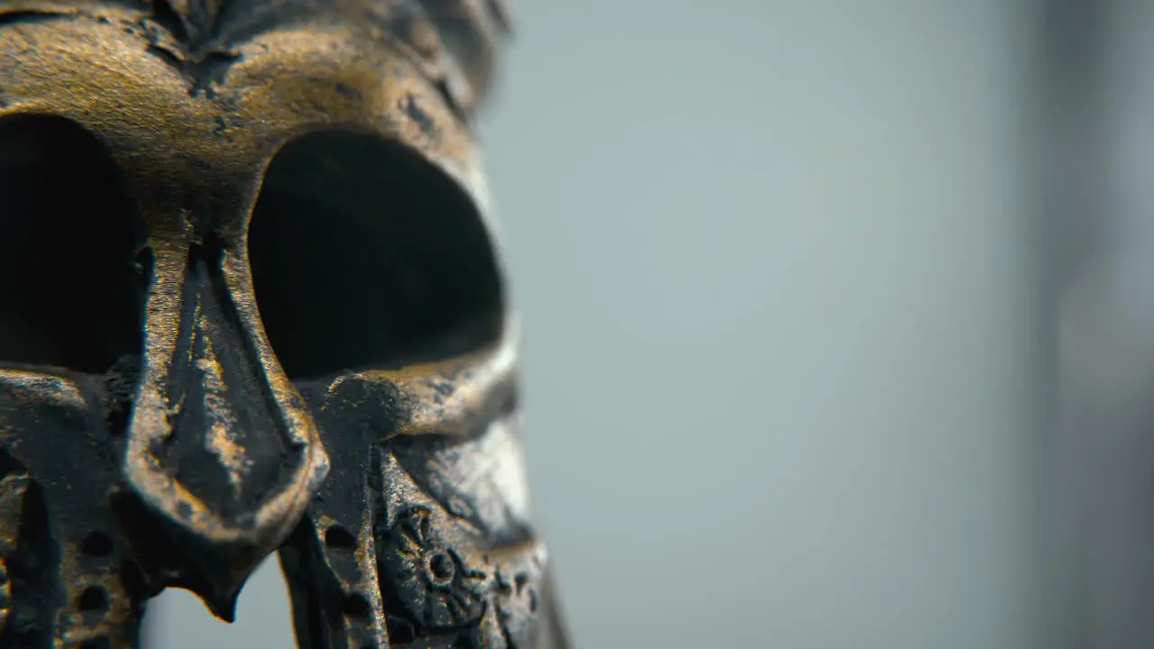 A close-up macro creative shot of a Spartan design two different ancient warrior metal bronze helmets glowing textured face mask shapes studio lighting 4K cinematic video Slow Motion pan left