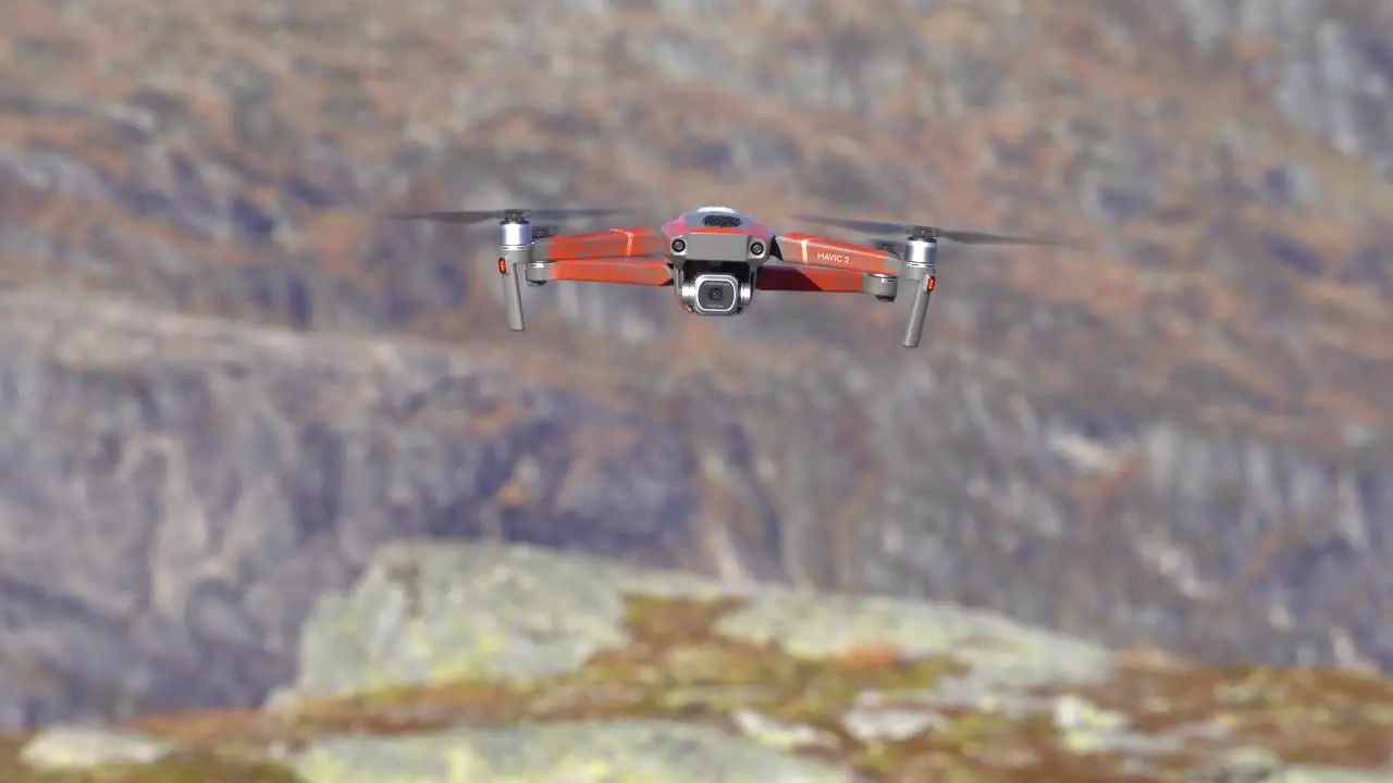 Drone with modern camera hovering close to camera before moving backwards and disappearing into blurred mountain landscape background Nesheim mountain in Vaksdal Norway