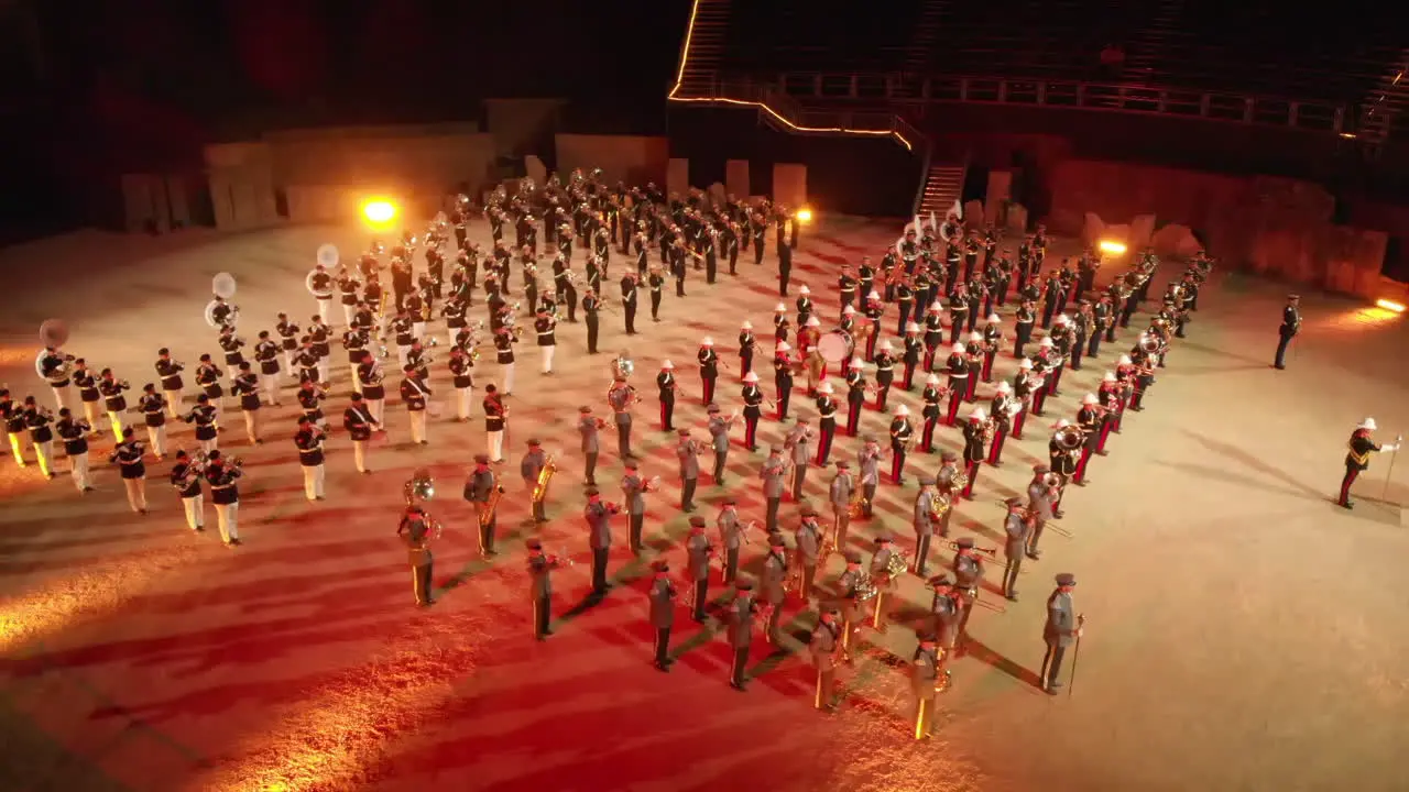 Drone shot orbiting around hundreds of musicians playing music in the arena in Avenches Switzerland