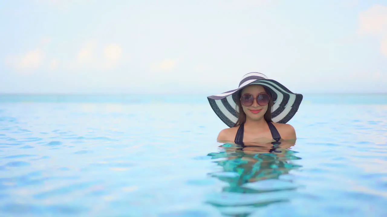 Asian model posing immersed in a pool in a swimsuit on vacation