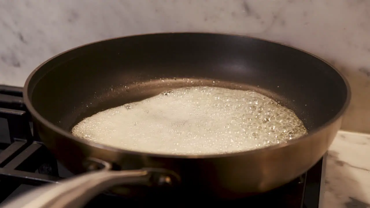 Handheld shot of hot butter being browned in a modern non-stick pan