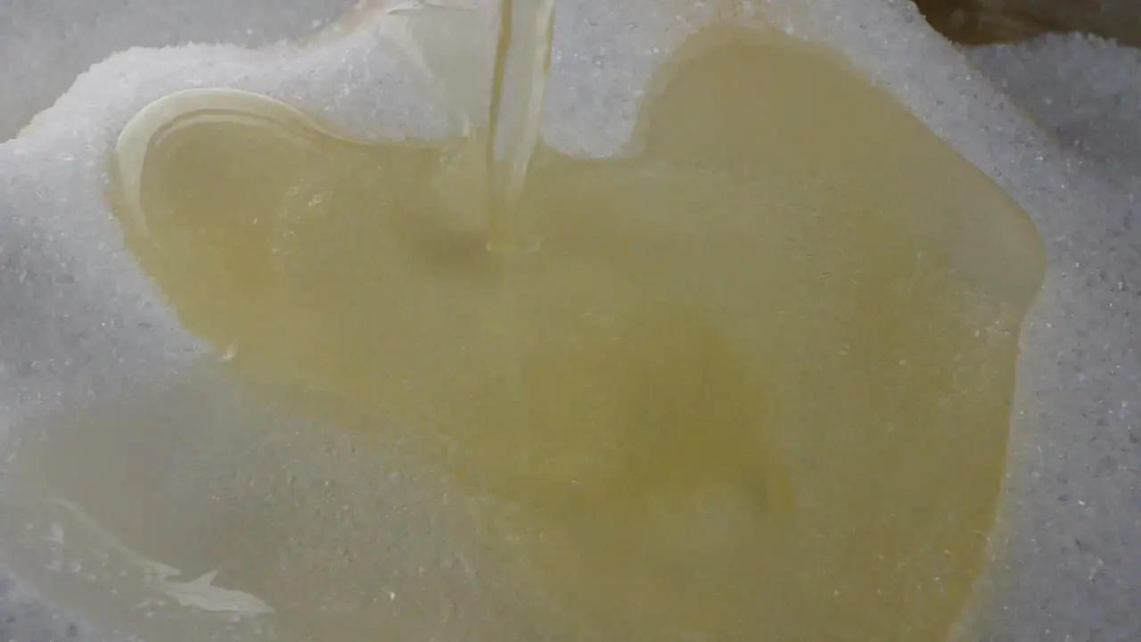 Close up of dropping a white and yellow egg yolk on white sugar while baking in slow motion