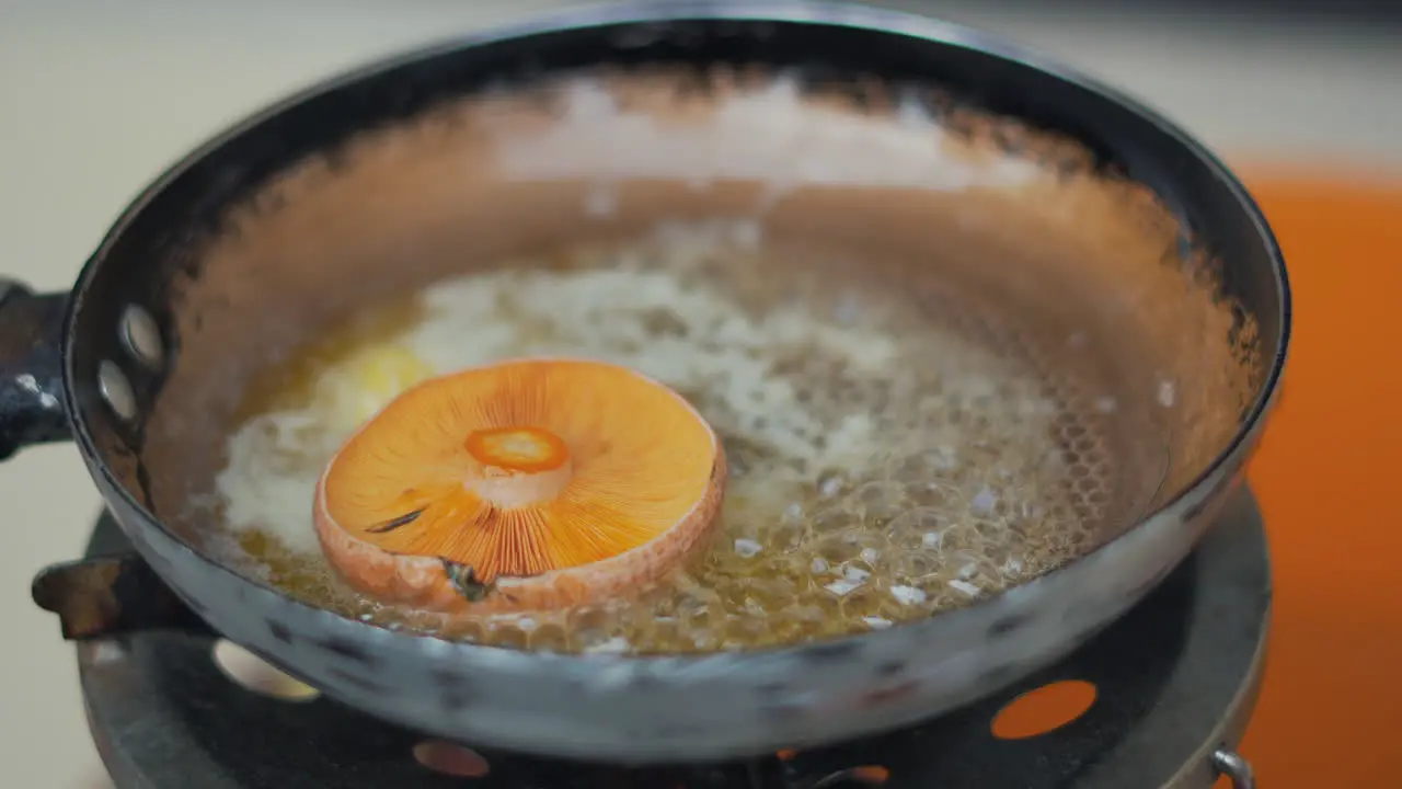 Putting mushroom on the frying pan at the camping