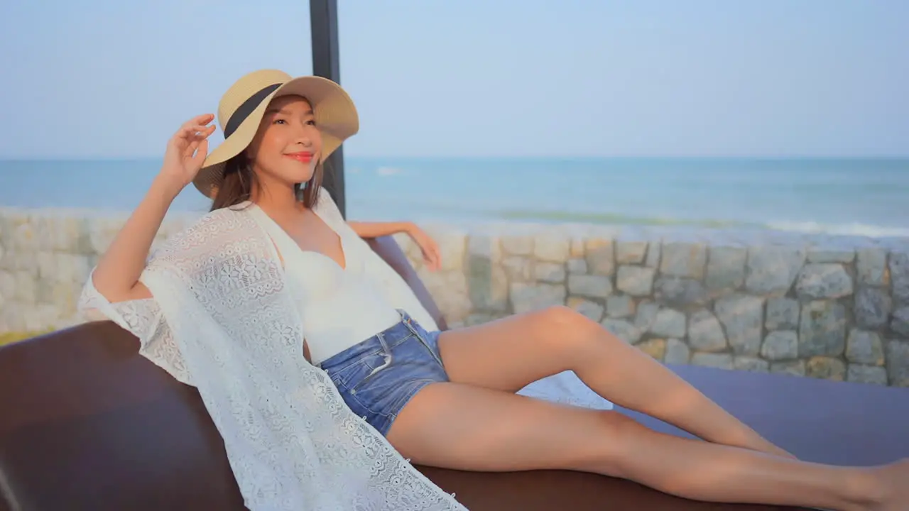 Smiling woman with hat relaxing on sunny day with sea in background