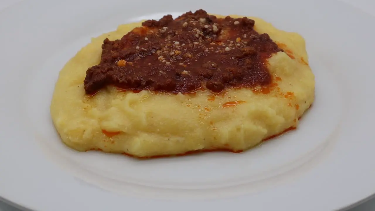 Polenta with bolognese sauce and parmesan cheese isolated on white