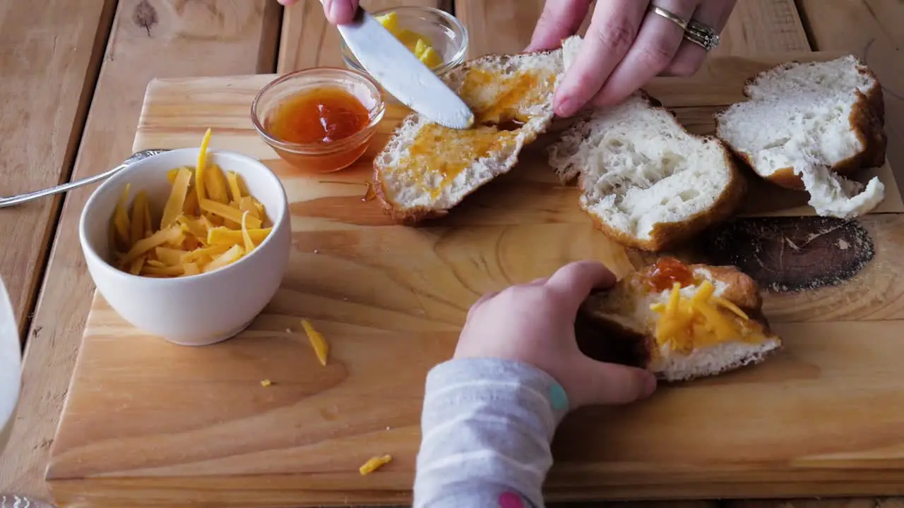 Mom preparing bread with jam cheese for hungry toddlers