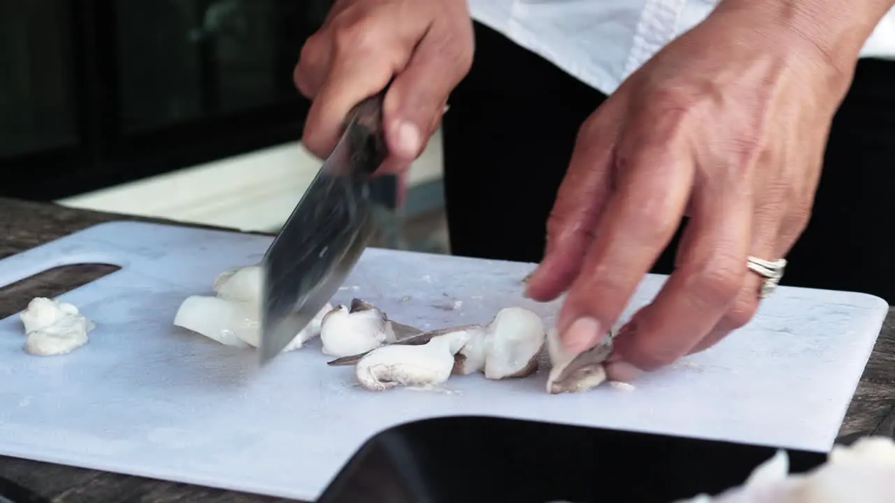 Recipe preparation Woman with ring cut squid into small pieces cutting white board