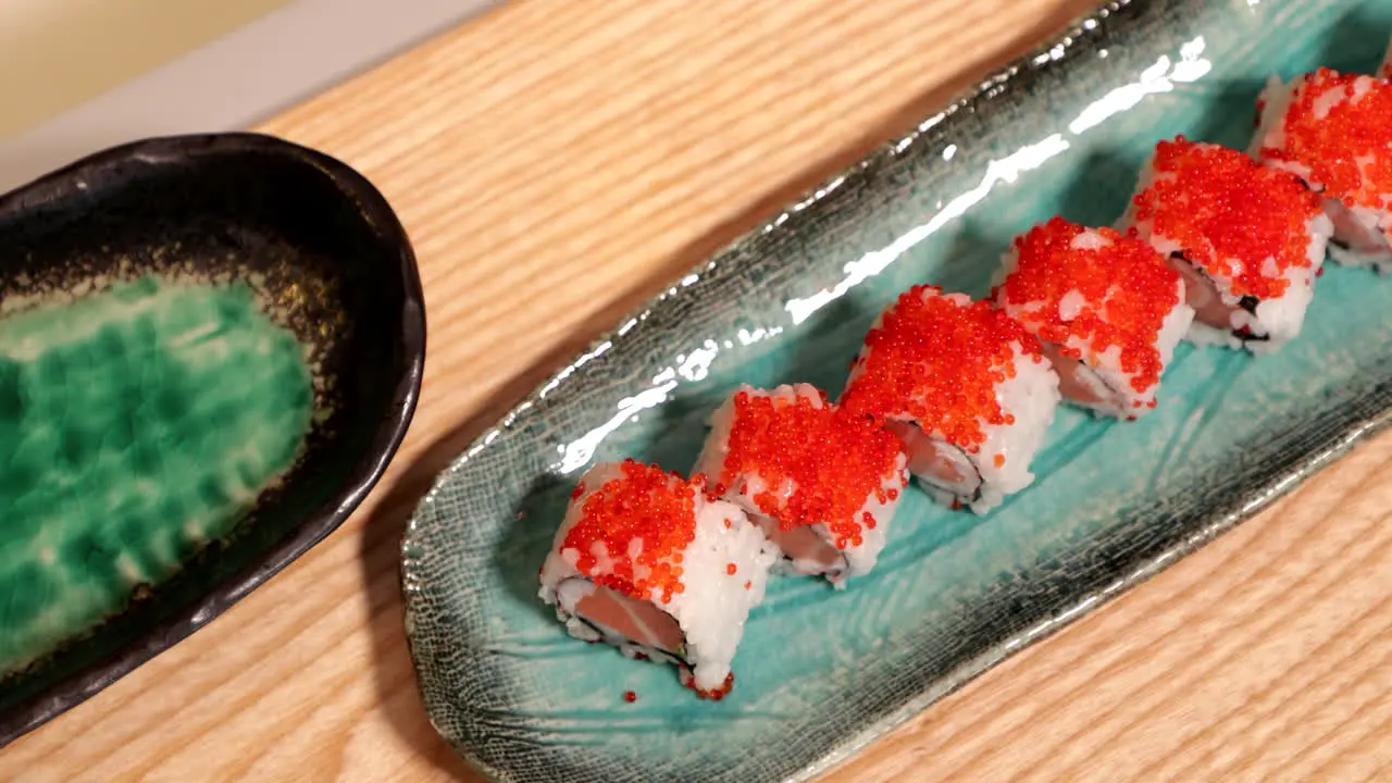 Delicious Sushi Rolls In A Plate Topped With Orange Roe high angle panning shot slow motion