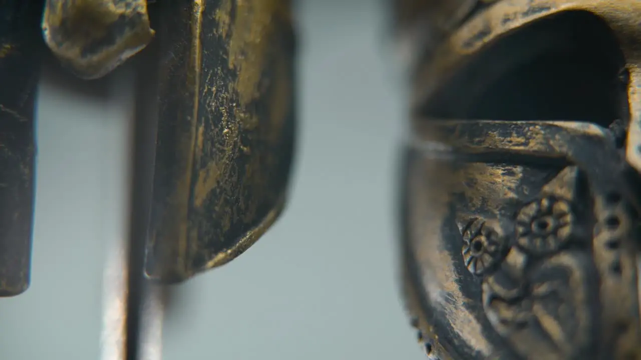 A close-up macro shot of a Spartan design two different ancient warrior metal bronze helmets textured shapes studio lighting Full HD cinematic video hyper Slow Motion 120 fps tilt up