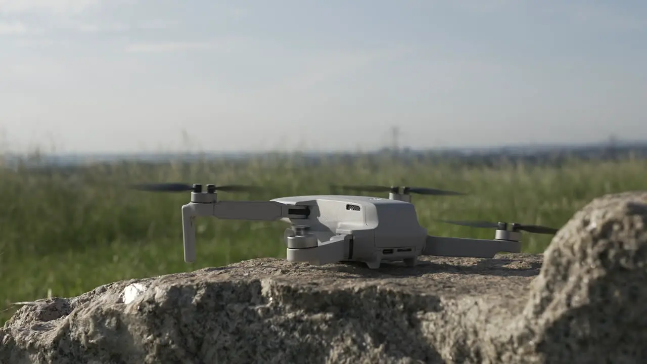 Drone Quadcopter Taking Off From Rock in Countryside Field on Sunny Day Close Up