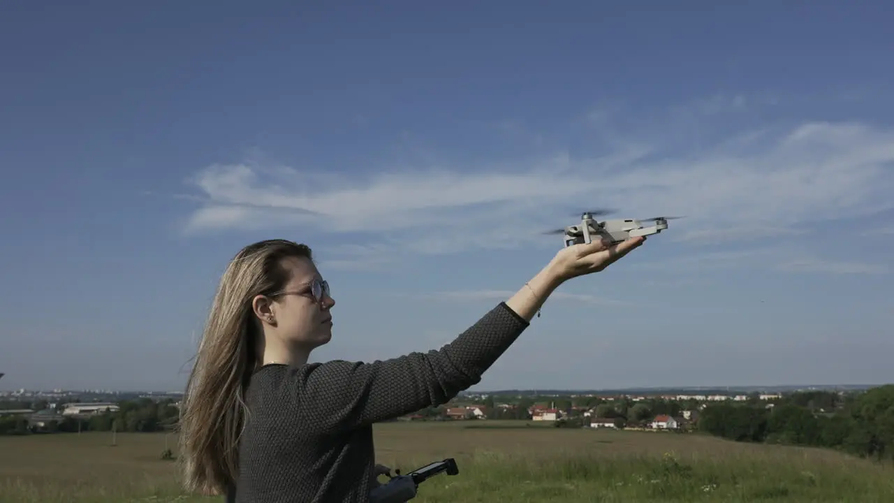 Young Woman Landing Consumer Quadcopter Drone on Her Hand at Sunny Day Slow Motion Full Frame