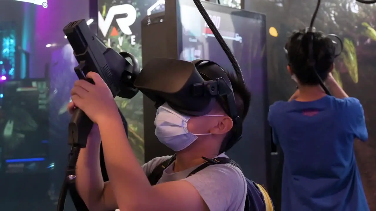 Chinese young gamers play a Virtual Reality shooting videogame as they reload point and shoot at targets during the Hong Kong Computer and Communications Festival in Hong Kong