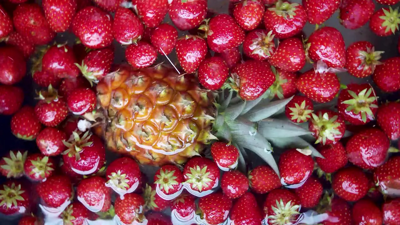 Pinapple and strawberry fruit spins and then stop floating in water