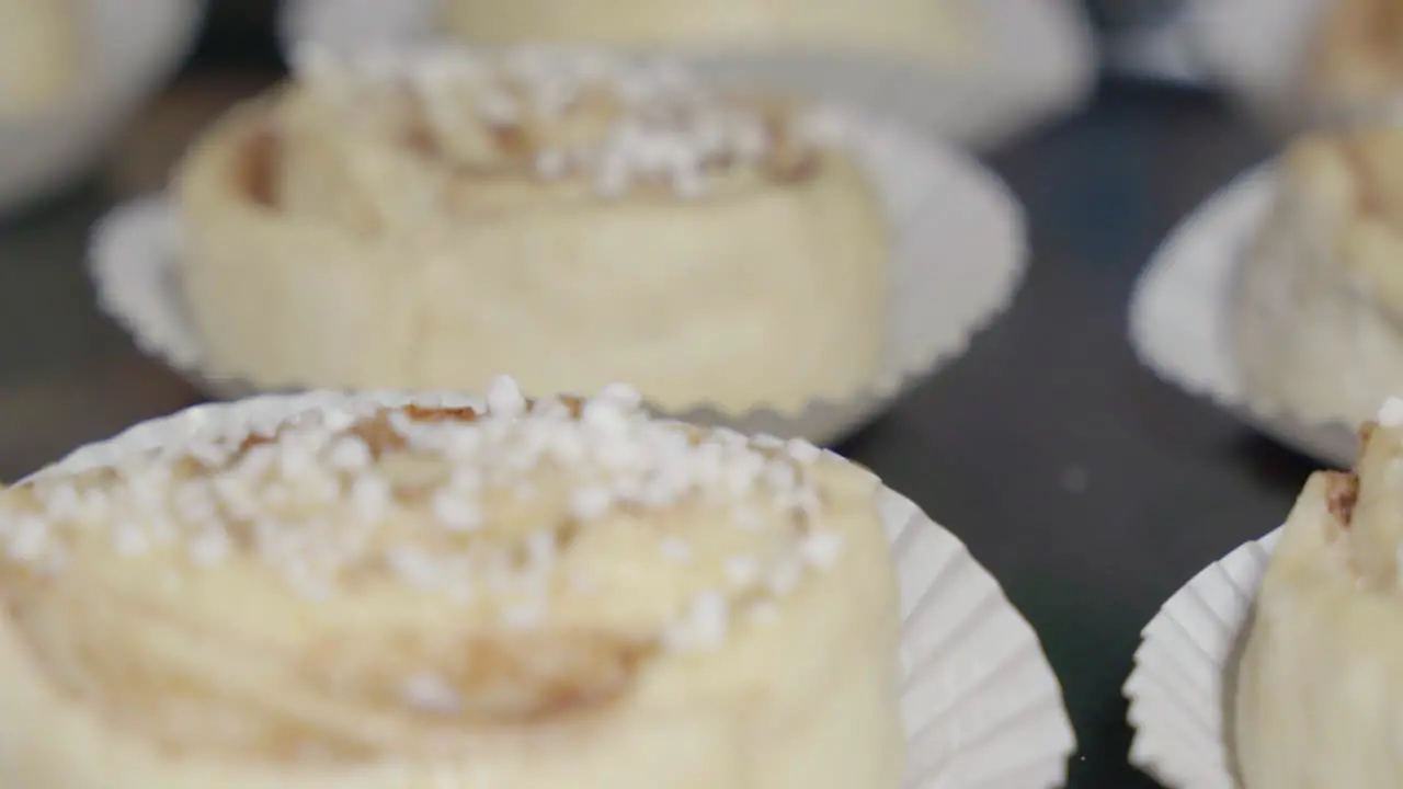 Close up slide shot of unbaked raw cinnamon buns on a tray