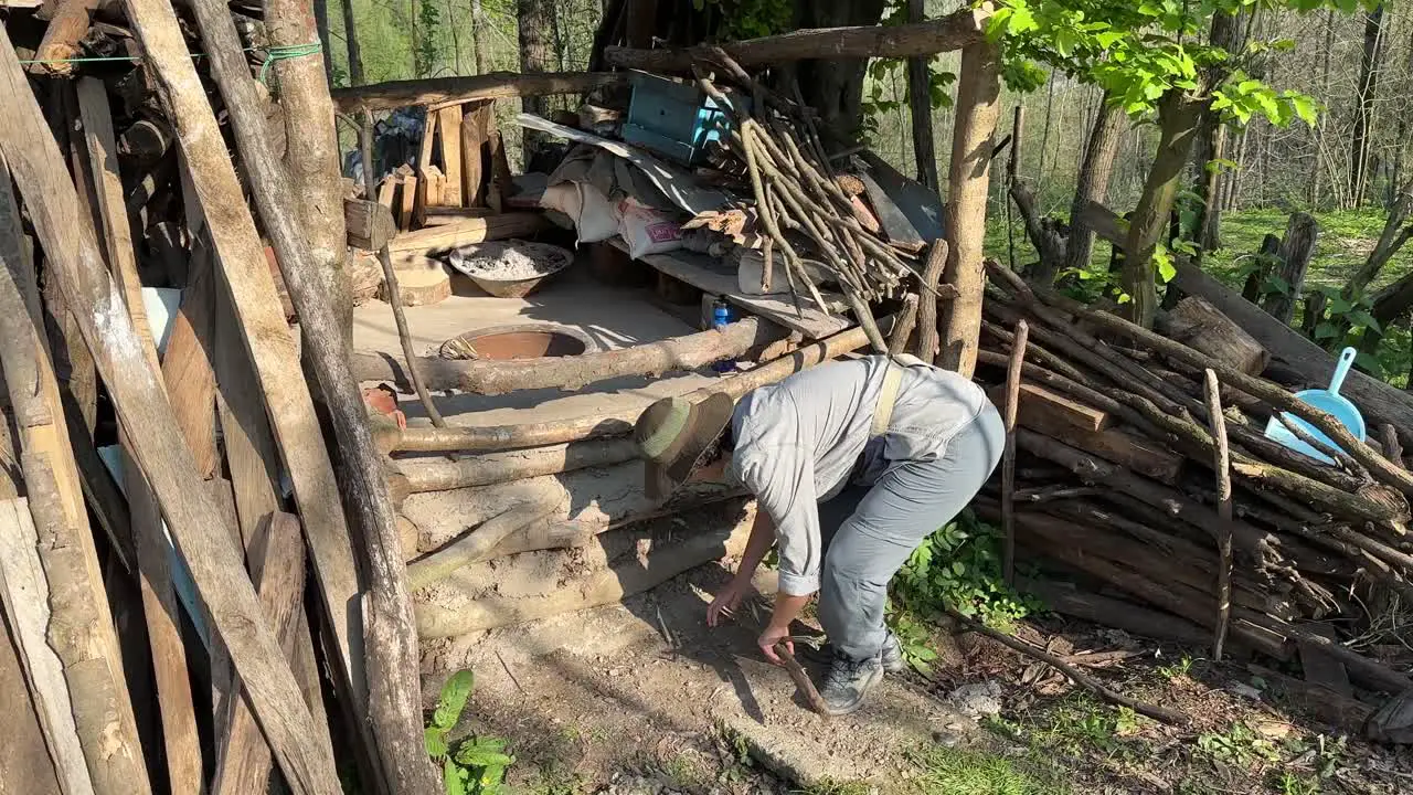 A woman try to break wood stick tree dry branches to make fire in a clay old traditional ground oven in a rural village to make flat Persian bread Lavash in Iran kneading dough and fermentation bakery