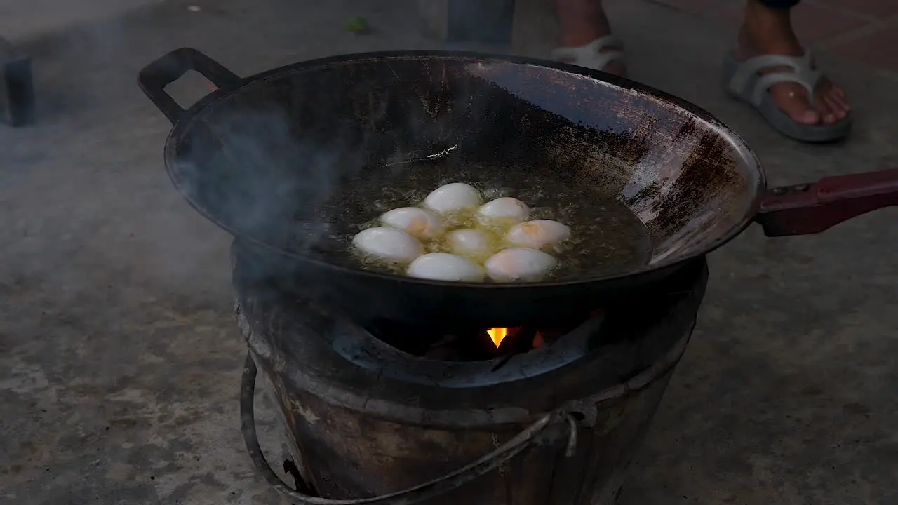 Motion Chef uses spatula to add duck eggs on rusty frying pan outdoors Street food