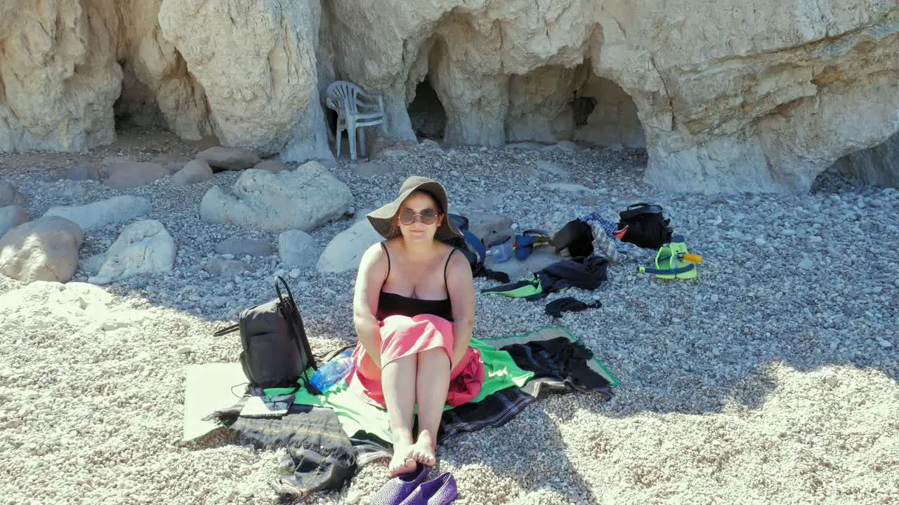 Tourist Woman Sitting On The Pebble Beach Of Agia Eleni In Greece wide static